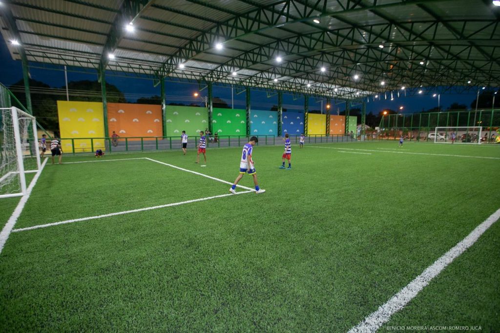 Crianças jogando futebol em campo society em Praça da Primeira Infância