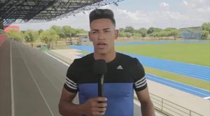 Deluan fala no microfone com pista de atletismo ao fundo