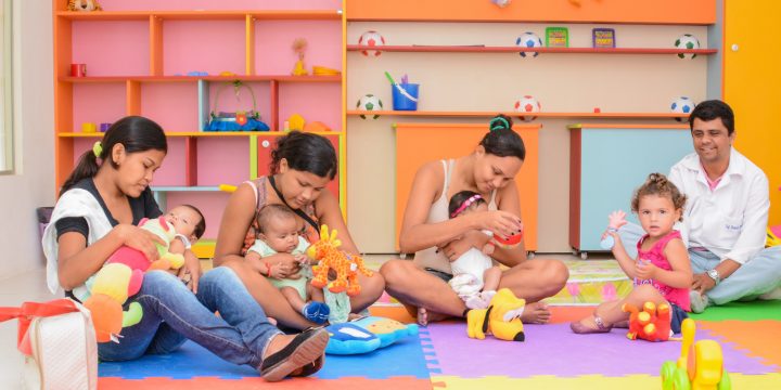 Mães brincando com seus filhos em brinquedoteca e um pai com o filho no mesmo ambiente