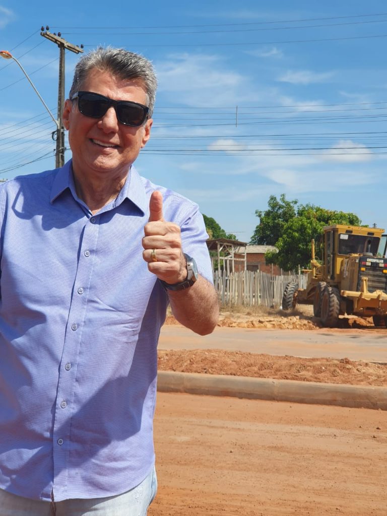 Romero Jucá faz sinal de legal enquanto visita obra de asfalto no Jardim Tropical