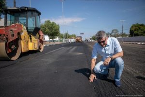 Jucá agachado e olhando para rua sendo asfaltada em Boa Vista