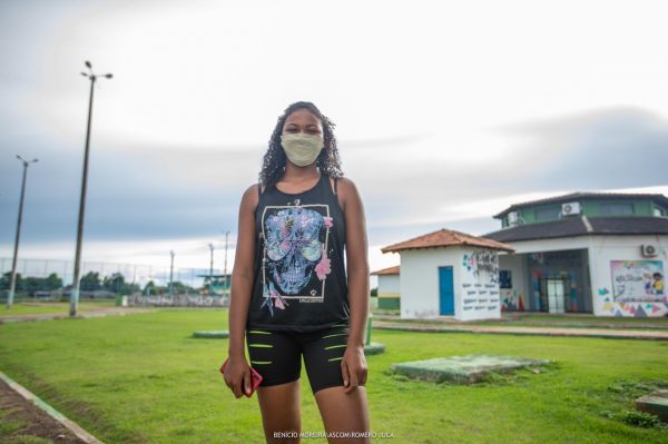 Jéssica de camiseta e short pretos em frente à Estação da Juventude