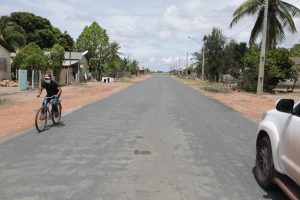 Imagem de rua asfaltada tem carro e homem pedalando. Asfalto é resultado do trabalho de senador em Normandia