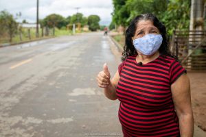 Ilda Mota faz sinal de positivo na rua em que mora. Lugar asfaltado é fruto da parceria com Iracema de Jucá