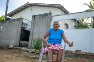 Leonice da Silva sentada na frente da casa dela. Trabalho de senador em Mucajaí asfaltou diversas ruas 