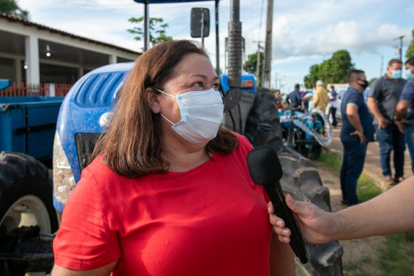 Prefeita Nega dando entrevista ao lado de um dos Tratores entregue