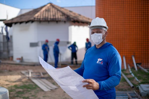 Magno Félix segura uma planta baixa em obra. Ele é um dos beneficiados com a geração de empregos