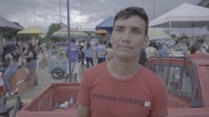 Wagner Vieira de camisa vermelha sorrindo. Ele vende chocolates na primeira Praça de Vista Alegre