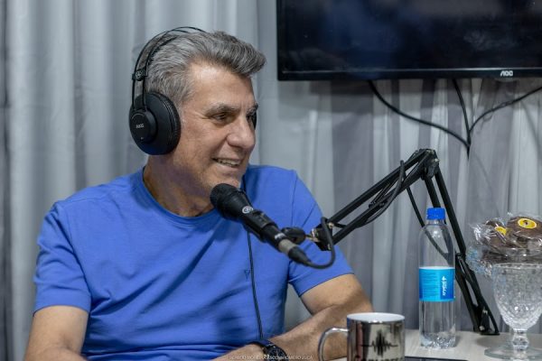 Romero Jucá em estúdio sorrindo ao falar no microfone. Conversa com Romero Jucá é descontraída